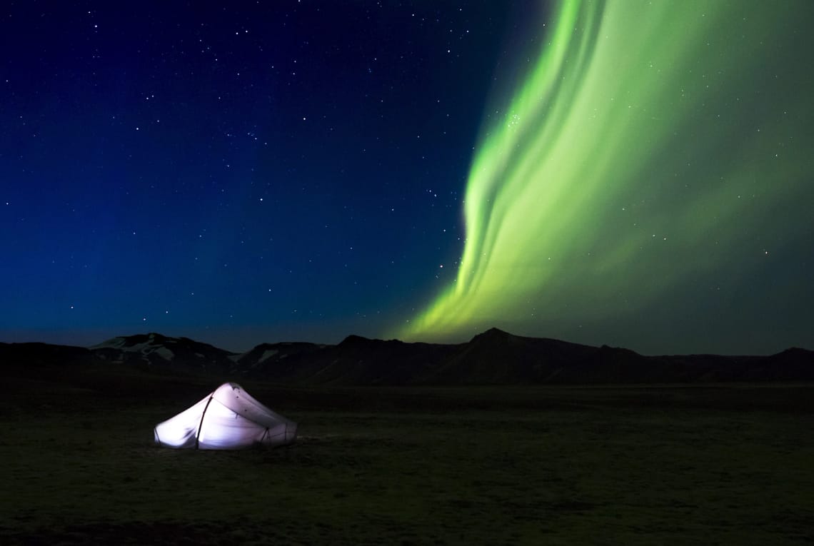 Nordlichter über einem erleuchtetem Zelt